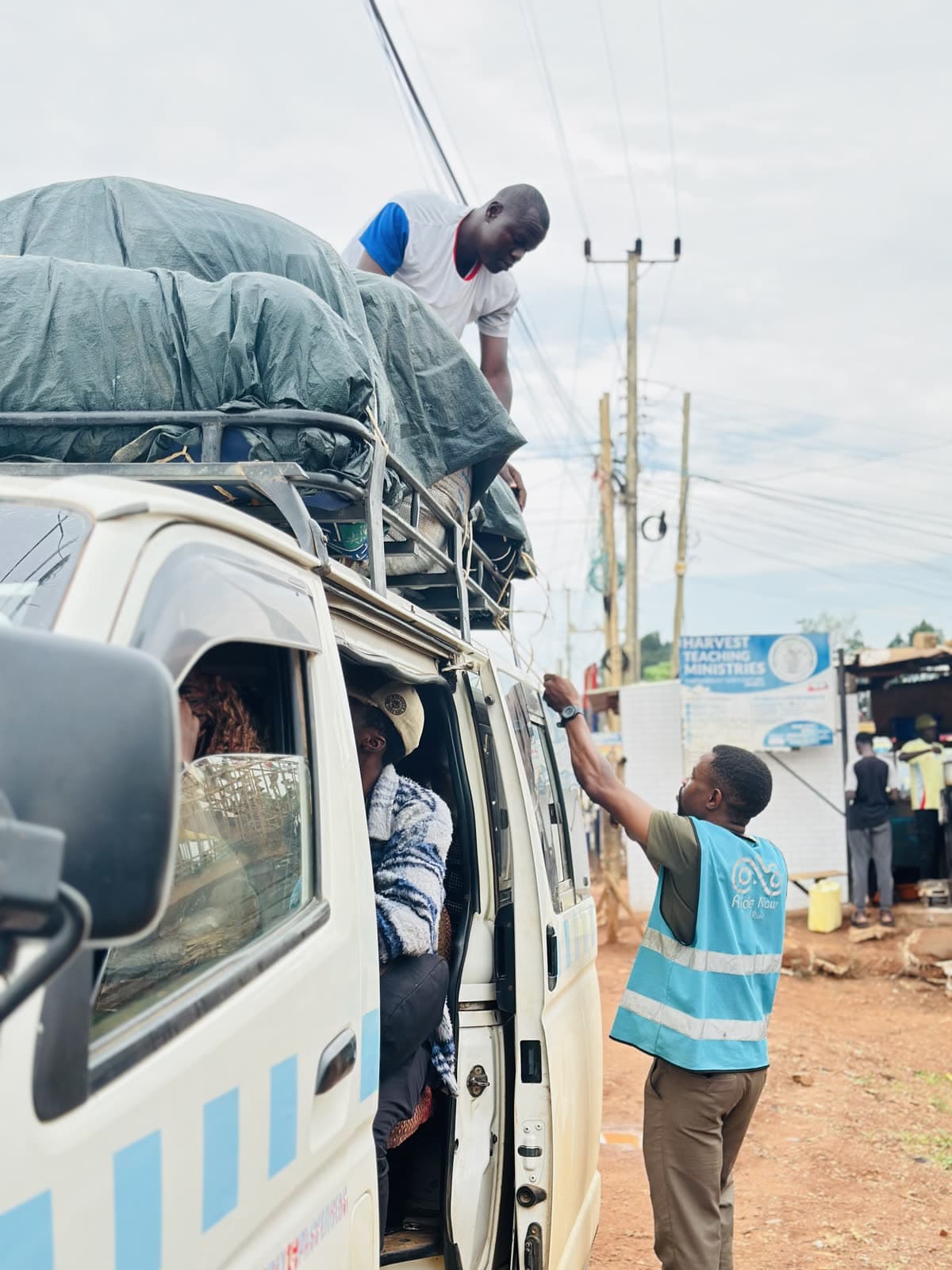 A group of people and a conductor loading a taxi in Uganda